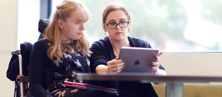 Two women, one using a wheelchair sitting in front of a laptop